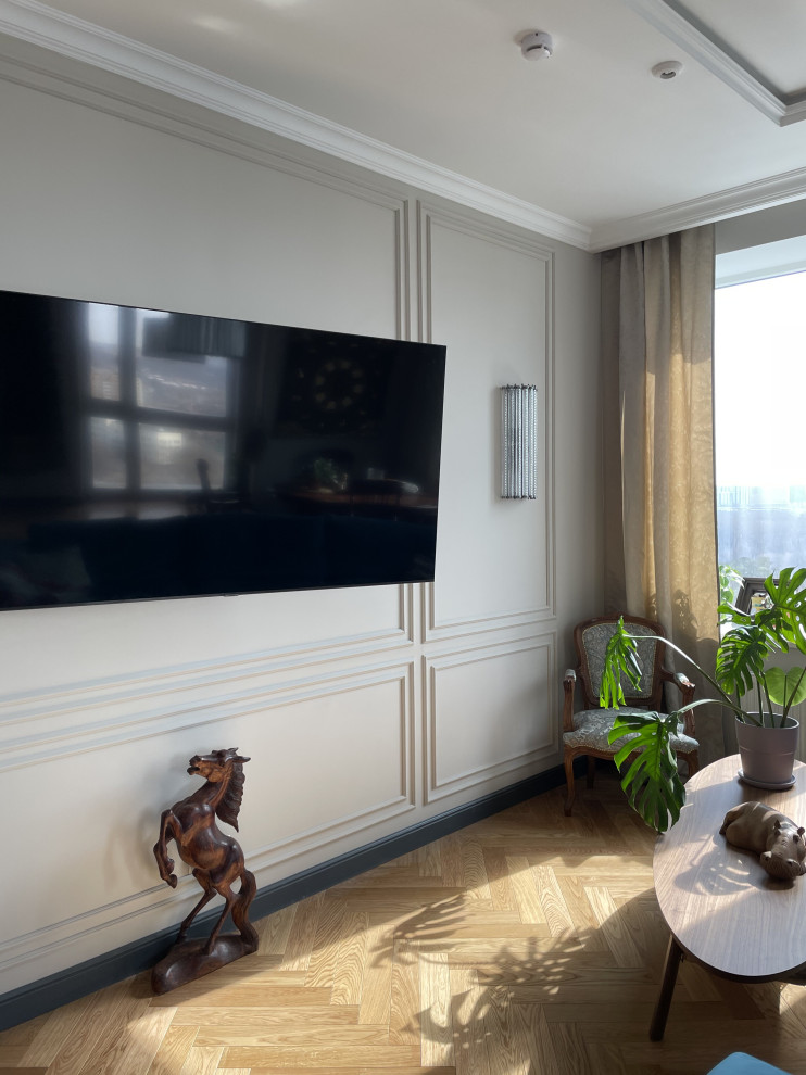 Стильный дизайн: большая гостиная комната в белых тонах с отделкой деревом в стиле неоклассика (современная классика) с бежевыми стенами, паркетным полом среднего тона, телевизором на стене, зоной отдыха и синим диваном - последний тренд