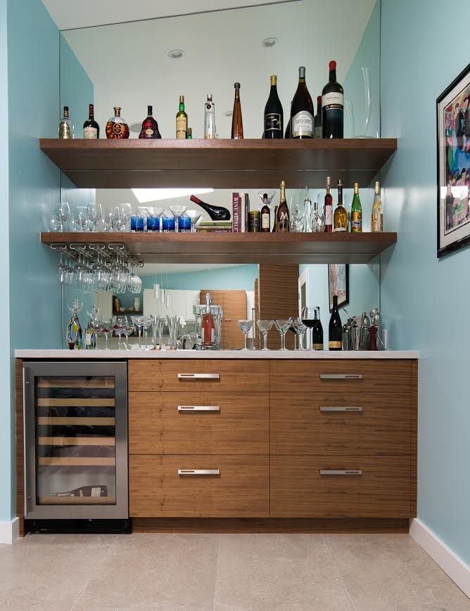 Inspiration for a mid-sized contemporary single-wall wet bar in Los Angeles with flat-panel cabinets, medium wood cabinets, solid surface benchtops, porcelain floors and mirror splashback.