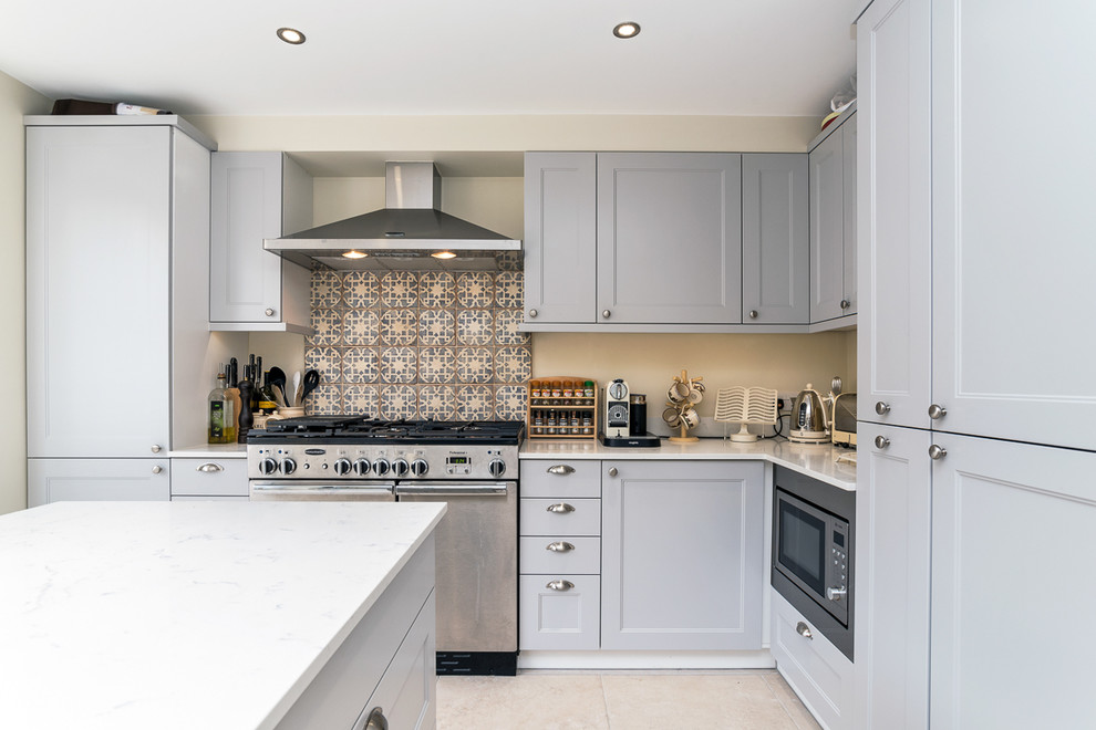 Inspiration for a transitional l-shaped kitchen in London with recessed-panel cabinets, multi-coloured splashback, stainless steel appliances, with island and grey cabinets.