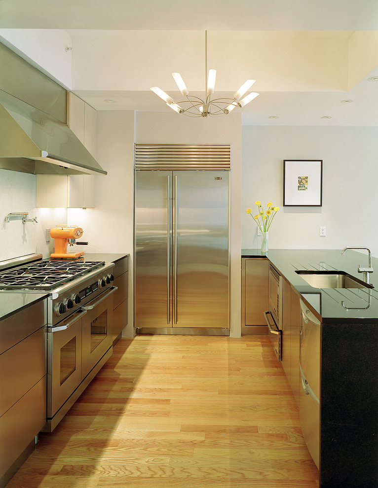 Photo of a contemporary u-shaped kitchen in Boston with stainless steel appliances, an undermount sink, flat-panel cabinets and stainless steel cabinets.