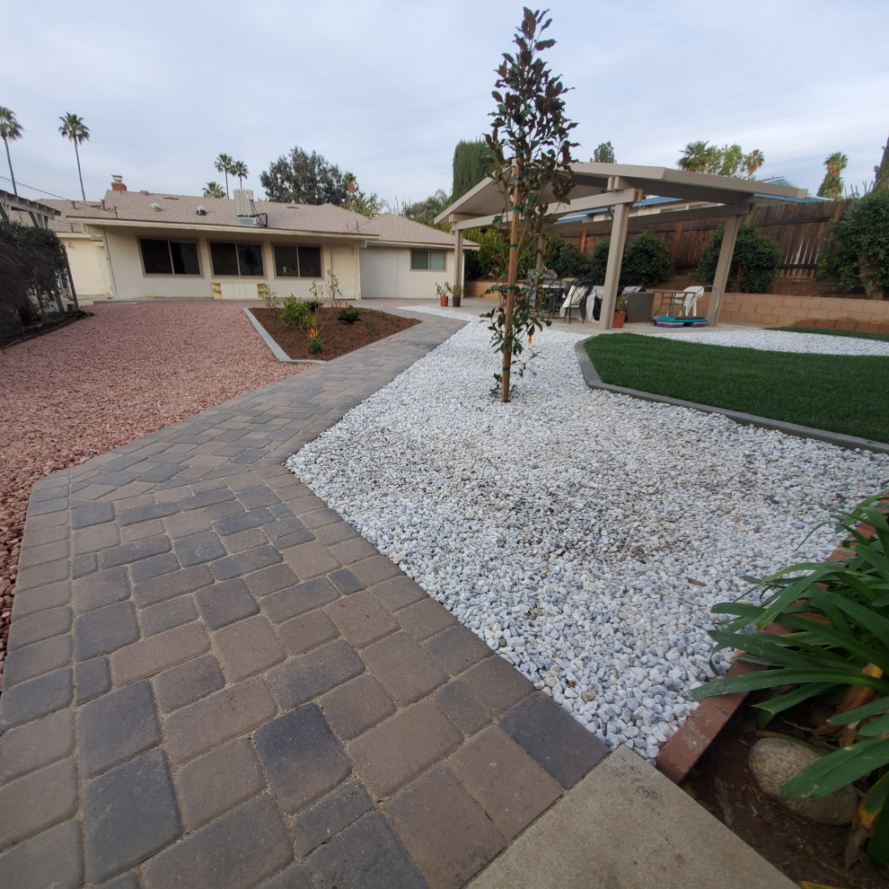 Design ideas for a large transitional backyard full sun xeriscape for spring in Los Angeles with a retaining wall, concrete pavers and a stone fence.