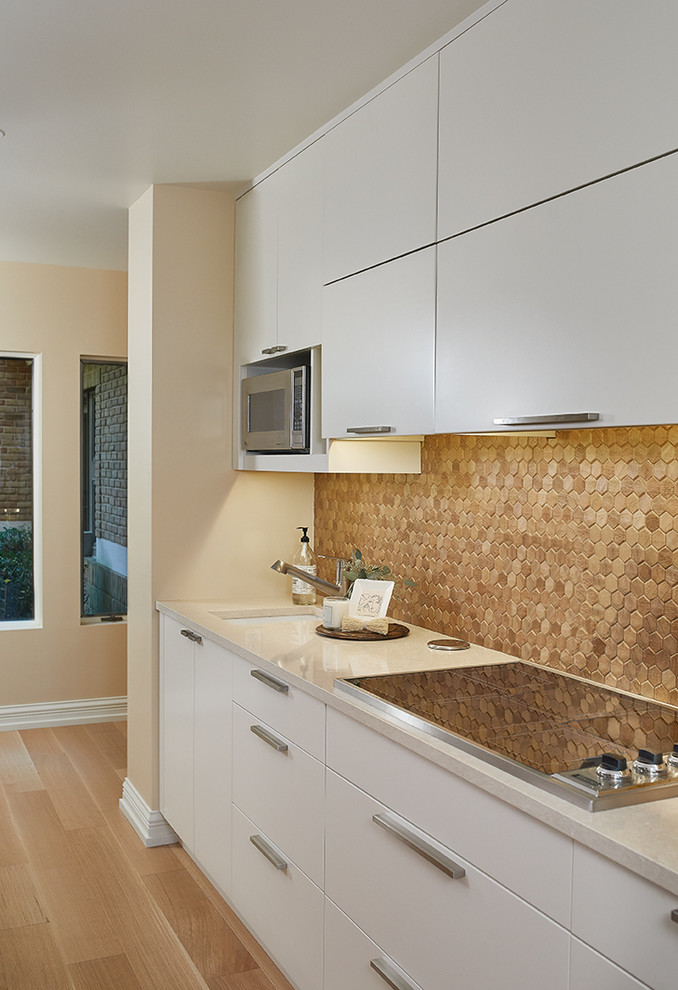 Inspiration for a transitional u-shaped light wood floor and beige floor eat-in kitchen remodel with an undermount sink, flat-panel cabinets, white cabinets, brown backsplash, stainless steel appliances, an island and beige countertops