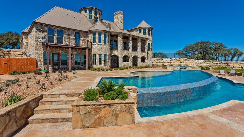 Country backyard custom-shaped infinity pool in Austin with a water feature.