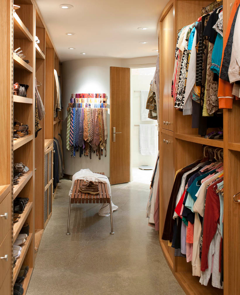 Imagen de vestidor unisex actual grande con armarios abiertos, puertas de armario de madera oscura y suelo de cemento