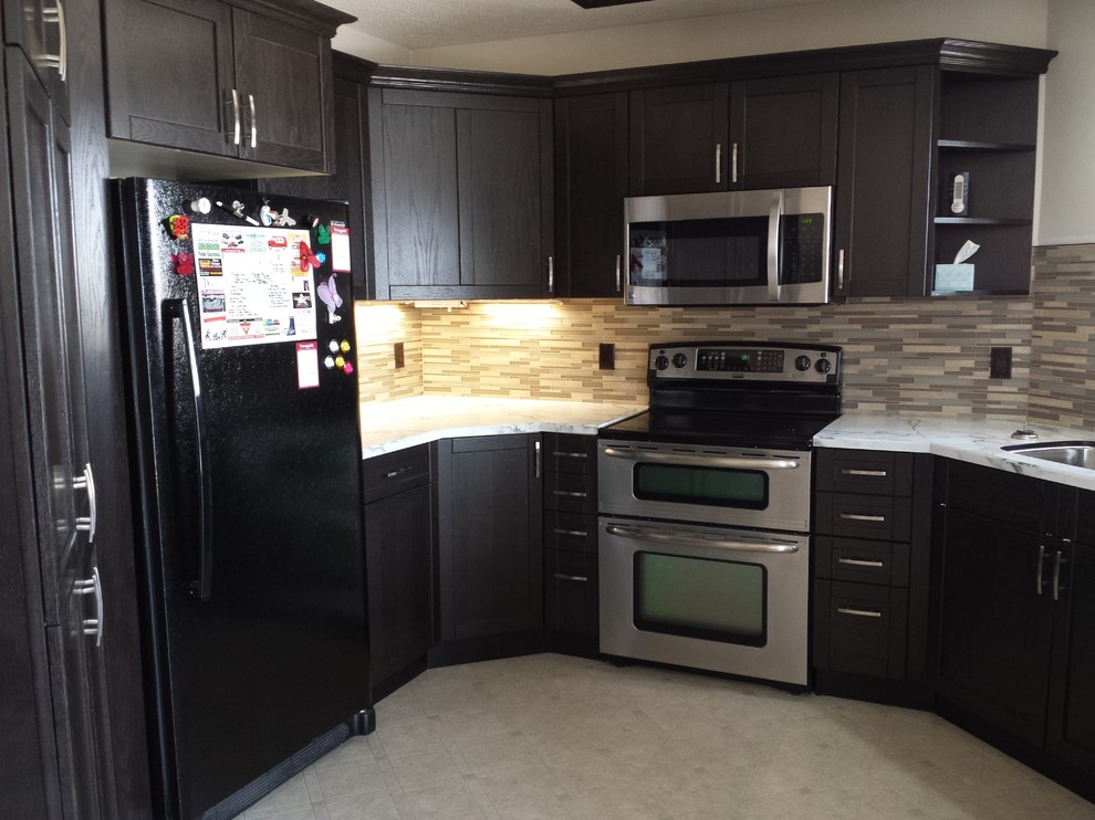 Enclosed kitchen - mid-sized transitional u-shaped ceramic tile and beige floor enclosed kitchen idea in Calgary with an undermount sink, shaker cabinets, black cabinets, marble countertops, beige backsplash, matchstick tile backsplash, stainless steel appliances and no island