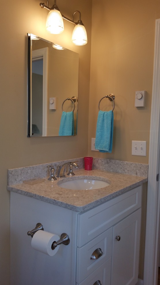 This is an example of a small contemporary 3/4 bathroom in Boston with recessed-panel cabinets, white cabinets, an alcove tub, a shower/bathtub combo, a two-piece toilet, multi-coloured tile, beige walls, ceramic floors, an undermount sink and granite benchtops.