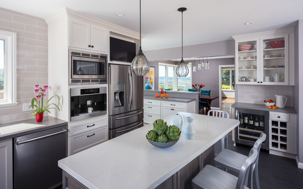 Large transitional u-shaped eat-in kitchen in San Francisco with shaker cabinets, white cabinets, grey splashback, stainless steel appliances, with island, a single-bowl sink, solid surface benchtops, subway tile splashback and porcelain floors.