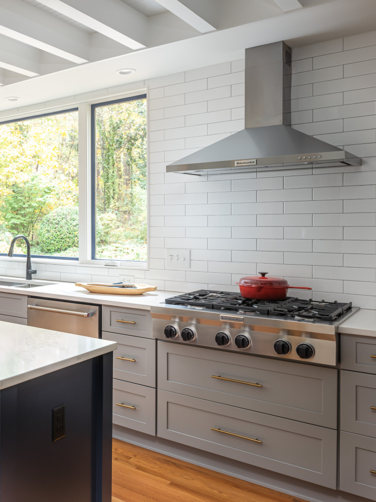 Inspiration for a mid-sized transitional u-shaped medium tone wood floor and brown floor open concept kitchen remodel in Raleigh with an undermount sink, recessed-panel cabinets, blue cabinets, quartzite countertops, white backsplash, subway tile backsplash, stainless steel appliances, an island and white countertops
