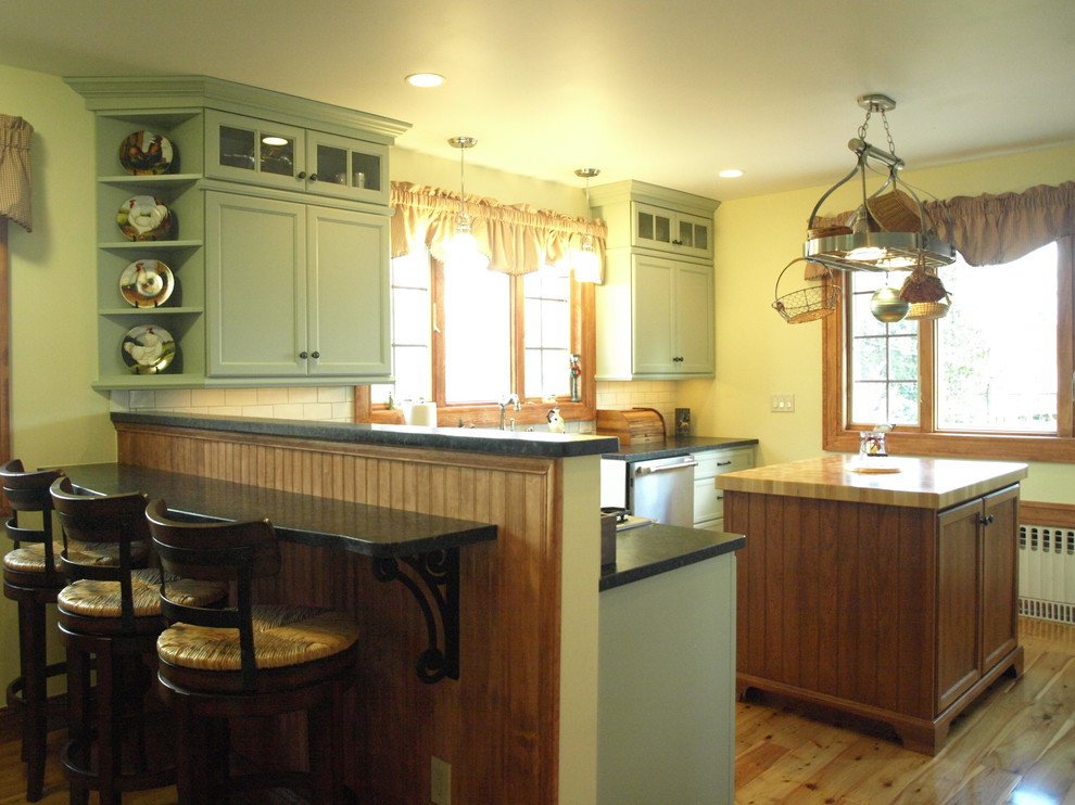 Photo of a mid-sized country l-shaped eat-in kitchen in Newark with a farmhouse sink, flat-panel cabinets, green cabinets, marble benchtops, white splashback, ceramic splashback, stainless steel appliances, medium hardwood floors, with island and beige floor.