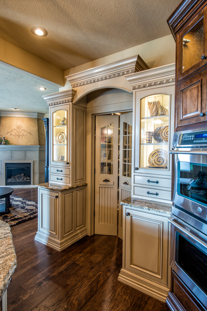 Large tuscan u-shaped dark wood floor kitchen pantry photo in Denver with beaded inset cabinets, beige cabinets, granite countertops, an island, an undermount sink, multicolored backsplash, stone tile backsplash and stainless steel appliances