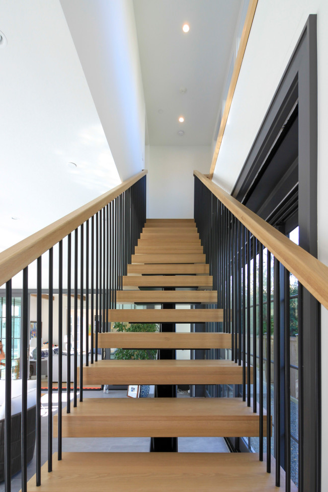 На фото: огромная лестница на больцах в стиле модернизм с деревянными ступенями, перилами из смешанных материалов и стенами из вагонки