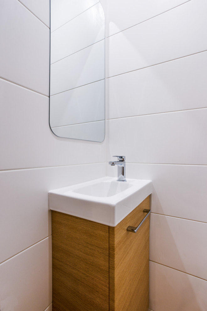 Réalisation d'un petit WC suspendu design avec un placard à porte plane, un carrelage blanc, des carreaux de céramique, un mur blanc, un lavabo intégré, un sol beige et meuble-lavabo suspendu.