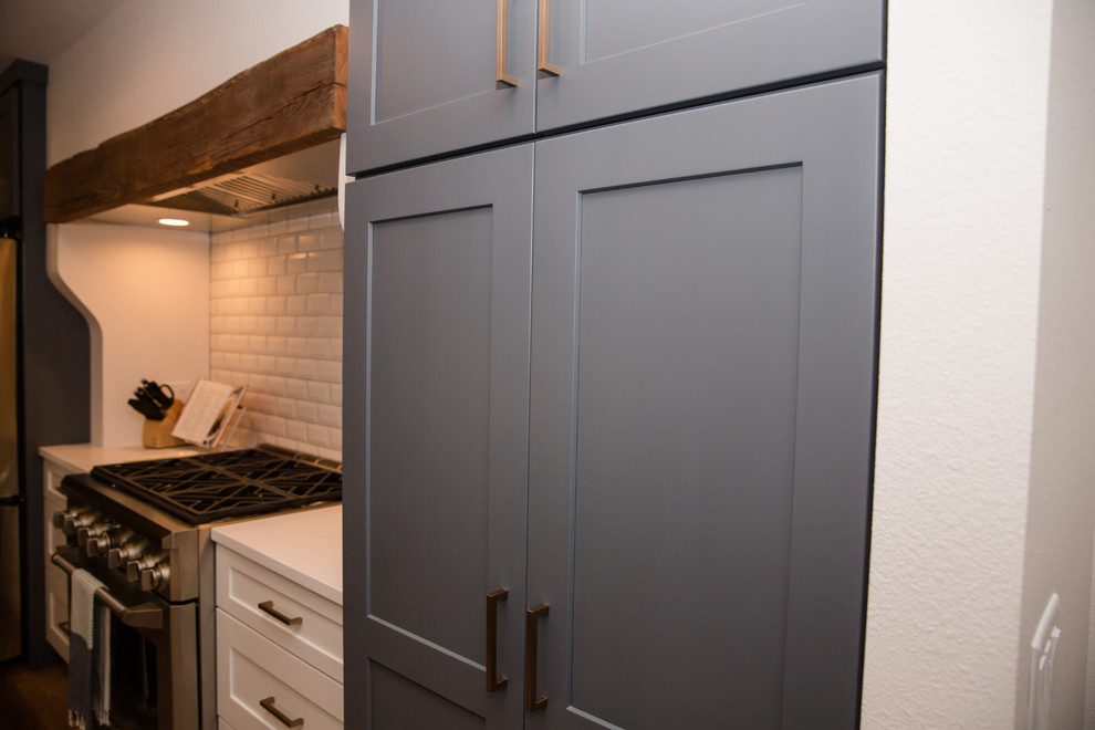 Eat-in kitchen - mid-sized transitional galley medium tone wood floor and brown floor eat-in kitchen idea with an undermount sink, shaker cabinets, blue cabinets, solid surface countertops, white backsplash, ceramic backsplash, stainless steel appliances, a peninsula and white countertops