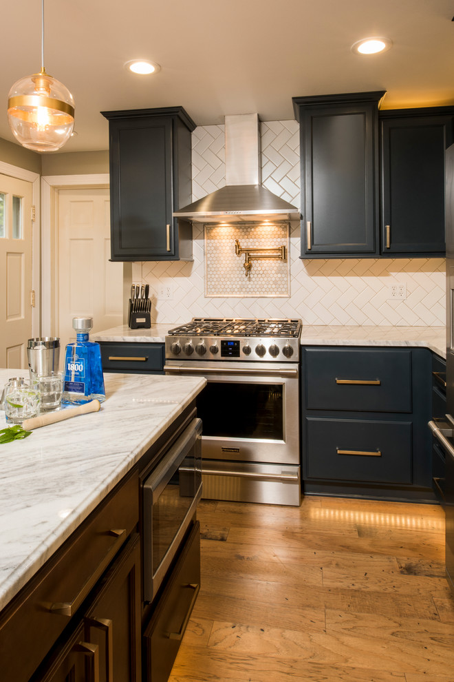 This is an example of a small country u-shaped separate kitchen in New York with a farmhouse sink, recessed-panel cabinets, blue cabinets, marble benchtops, white splashback, subway tile splashback, stainless steel appliances, medium hardwood floors and with island.