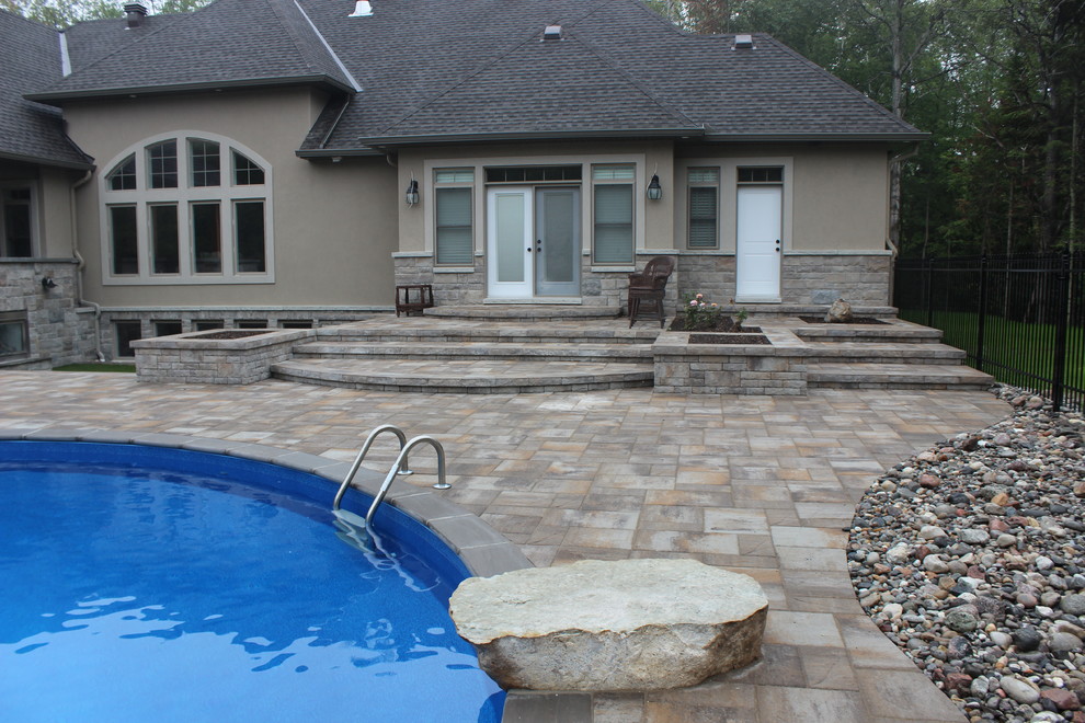 Inspiration for a large contemporary backyard kidney-shaped natural pool in Ottawa with a water feature and stamped concrete.
