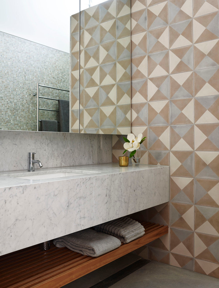 This is an example of a mid-sized contemporary master bathroom in Sydney with an integrated sink, marble benchtops, cement tile, open cabinets and multi-coloured tile.