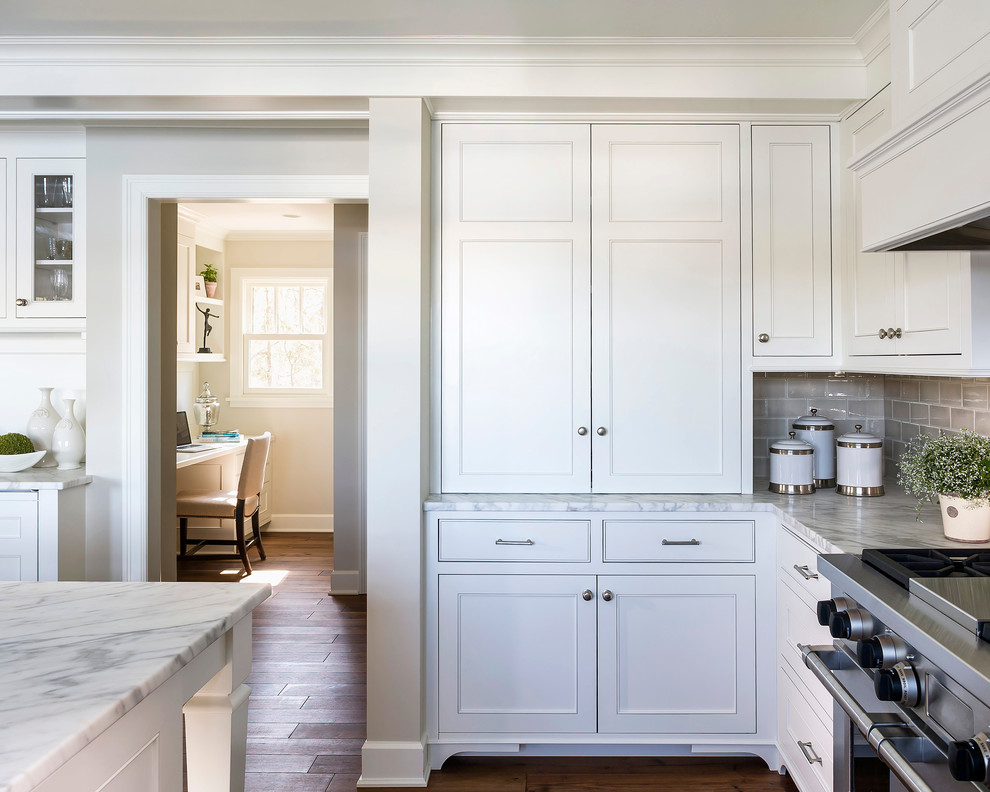 Photo of a mid-sized traditional l-shaped eat-in kitchen in Minneapolis with an undermount sink, recessed-panel cabinets, white cabinets, marble benchtops, beige splashback, ceramic splashback, panelled appliances, dark hardwood floors and with island.