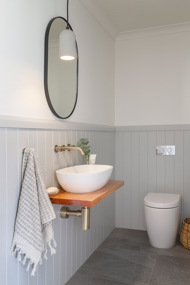 Cette image montre un petit WC et toilettes design avec un plan de toilette en bois et meuble-lavabo suspendu.