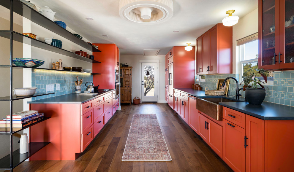 Inspiration for a mid-sized transitional galley eat-in kitchen in Austin with a farmhouse sink, shaker cabinets, red cabinets, quartz benchtops, blue splashback, ceramic splashback and black benchtop.