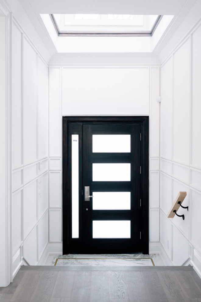 Foyer - transitional ceramic tile, gray floor, tray ceiling and wall paneling foyer idea in Toronto with white walls and a black front door