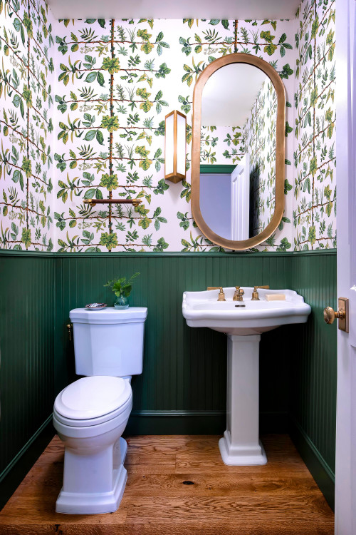Small transitional medium tone wood floor, brown floor and wallpaper powder room photo in Los Angeles with white cabinets, a one-piece toilet, green walls, a pedestal sink, white countertops and a freestanding vanity 