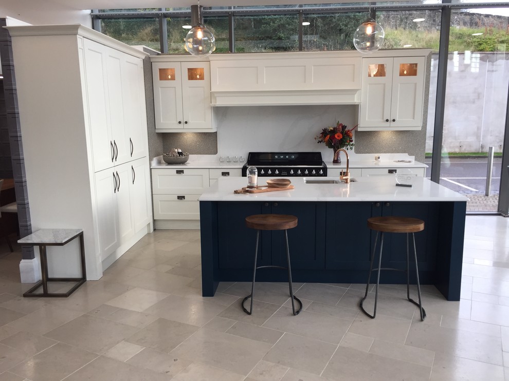 Photo of a mid-sized traditional l-shaped separate kitchen in Belfast with an integrated sink, beaded inset cabinets, quartzite benchtops, white splashback, stone slab splashback, black appliances, limestone floors, with island, grey floor and white benchtop.