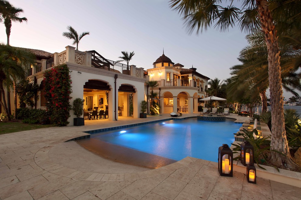 Inspiration for an expansive mediterranean backyard custom-shaped natural pool in Miami with natural stone pavers.