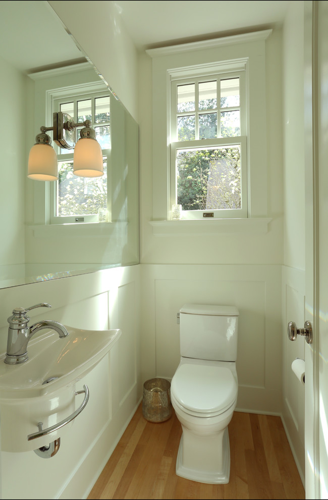 Inspiration for a small traditional bathroom in Portland with a wall-mount sink, white walls, light hardwood floors and a two-piece toilet.