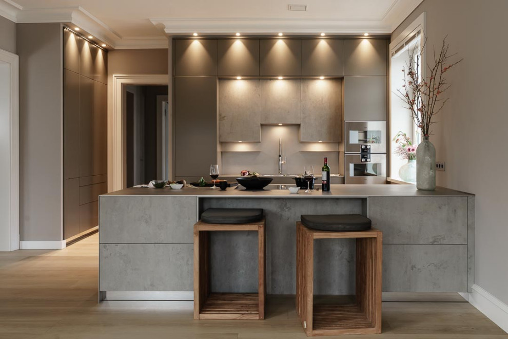 This is an example of an expansive modern eat-in kitchen in Hamburg with a single-bowl sink, flat-panel cabinets, stainless steel benchtops, light hardwood floors and a peninsula.