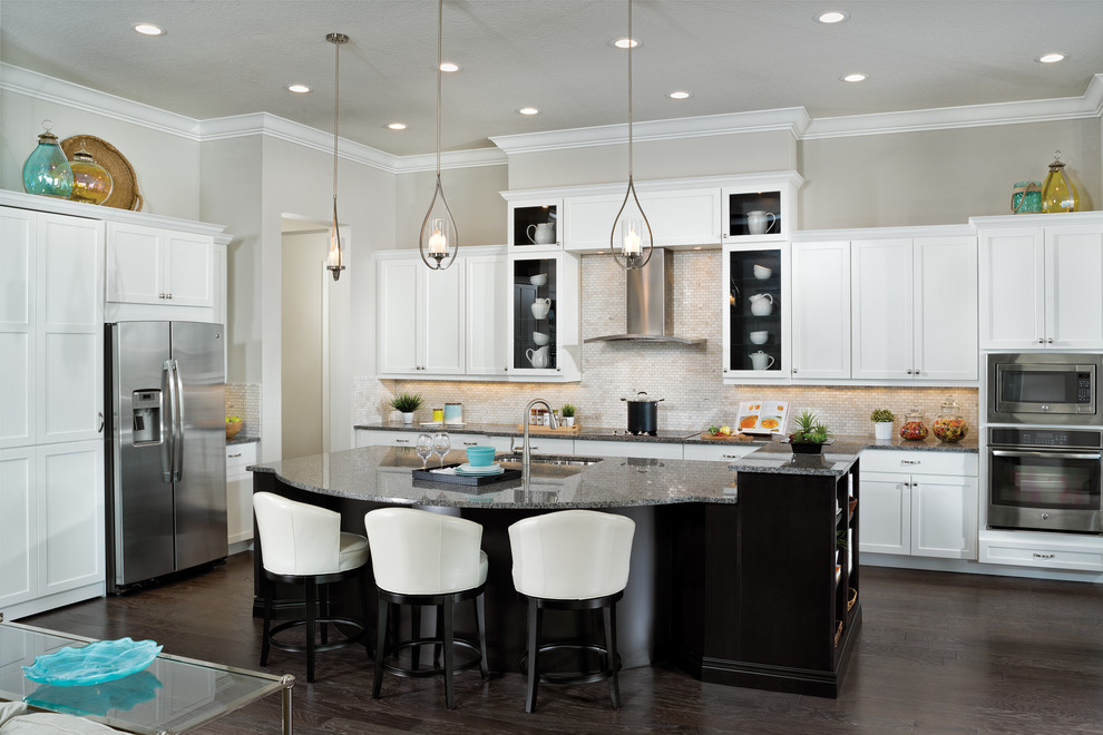 Design ideas for an expansive transitional l-shaped open plan kitchen in Tampa with an undermount sink, raised-panel cabinets, white cabinets, granite benchtops, beige splashback, ceramic splashback, stainless steel appliances, dark hardwood floors and with island.