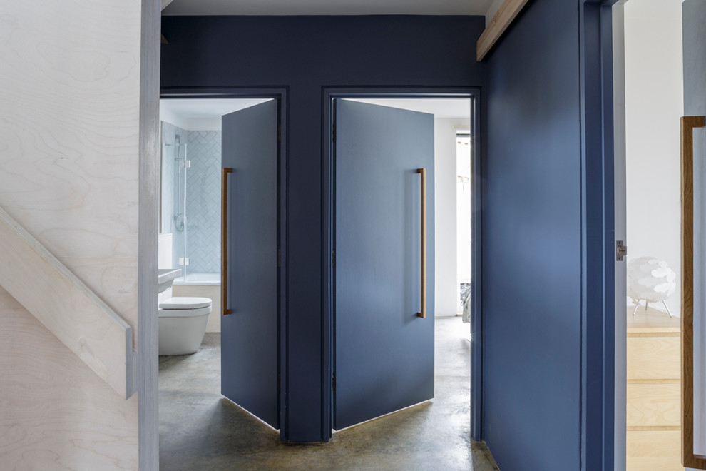 This is an example of a mid-sized contemporary hallway in Gloucestershire with blue walls and concrete floors.