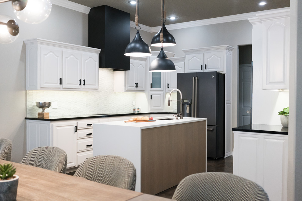 This is an example of a mid-sized modern u-shaped eat-in kitchen in Other with an undermount sink, raised-panel cabinets, white cabinets, quartz benchtops, white splashback, glass tile splashback, black appliances, dark hardwood floors, with island, black floor and white benchtop.
