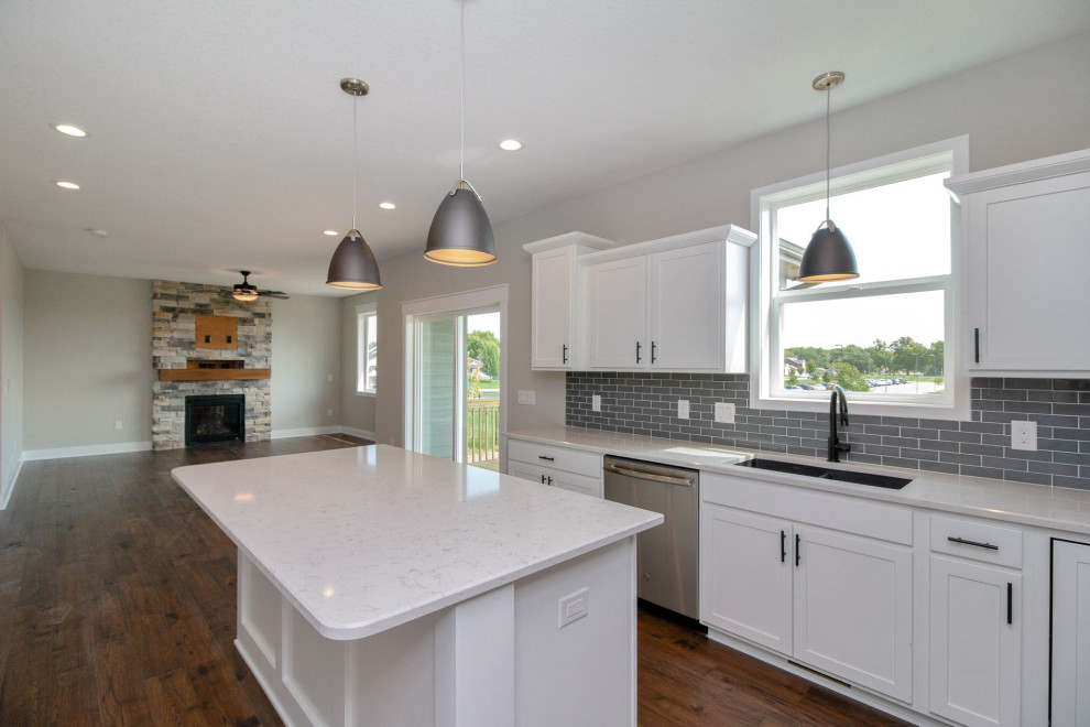 Kitchen - mid-sized transitional dark wood floor and brown floor kitchen idea with an undermount sink, shaker cabinets, white cabinets, quartz countertops, gray backsplash, subway tile backsplash, stainless steel appliances, an island and white countertops