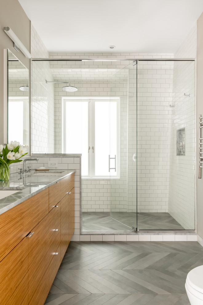 Design ideas for a large contemporary 3/4 bathroom in New York with flat-panel cabinets, medium wood cabinets, an alcove shower, white tile, subway tile, grey walls, an undermount sink, grey floor, a hinged shower door and grey benchtops.