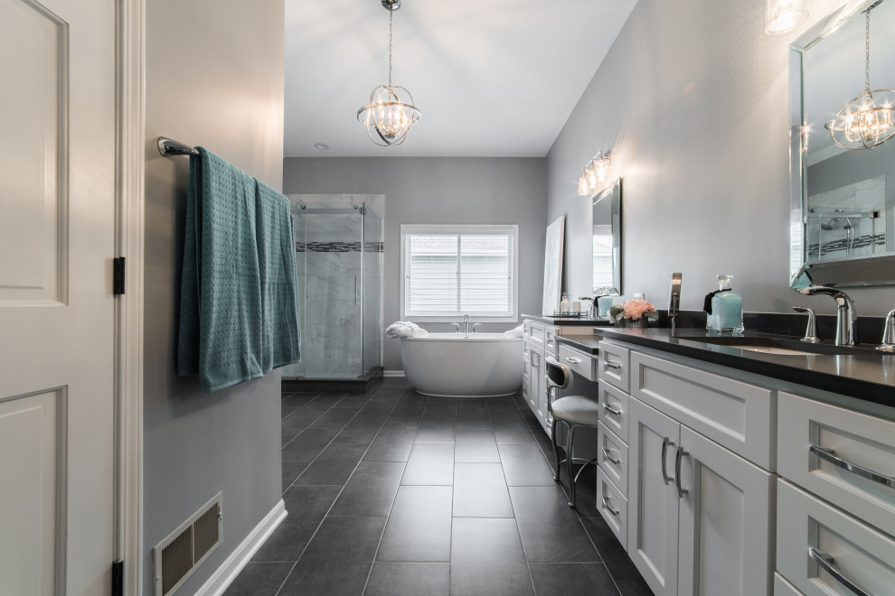 Inspiration for a mid-sized transitional master white tile and porcelain tile porcelain tile, gray floor, double-sink and vaulted ceiling freestanding bathtub remodel in Chicago with shaker cabinets, white cabinets, a two-piece toilet, gray walls, an undermount sink, solid surface countertops, gray countertops and a built-in vanity