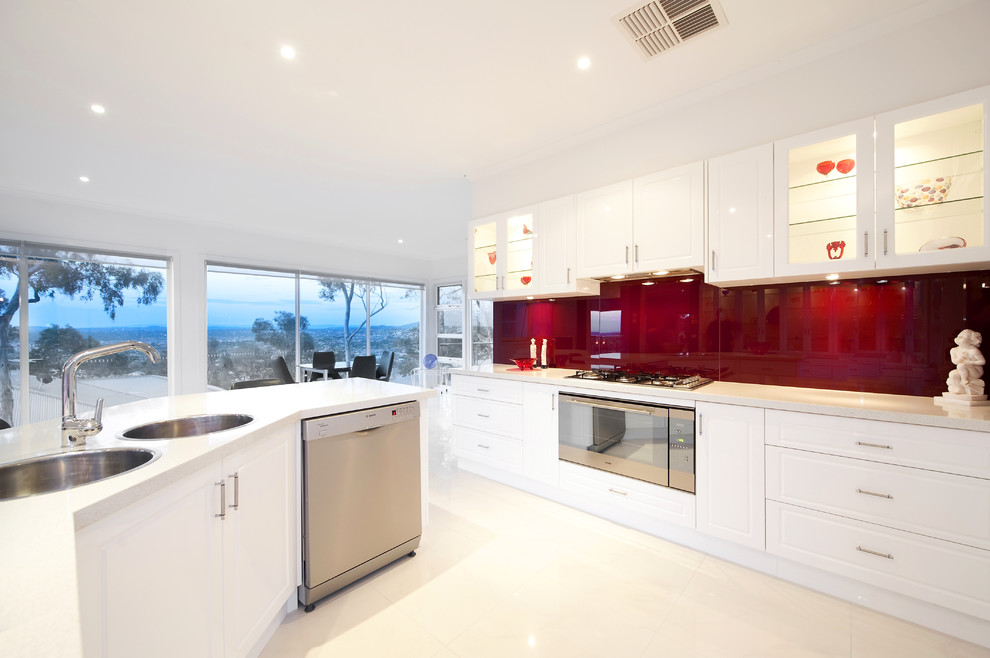 Design ideas for a contemporary eat-in kitchen in Melbourne with a drop-in sink, white cabinets, red splashback and stainless steel appliances.