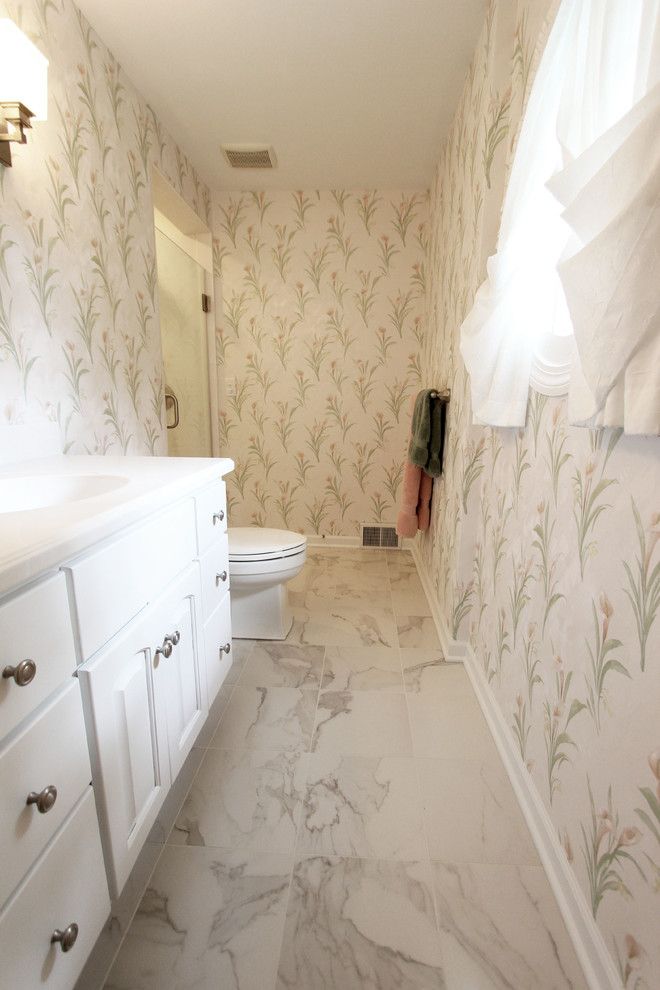 This is an example of a small traditional master bathroom in Cleveland with white cabinets, a corner shower, a one-piece toilet, white tile, multi-coloured walls, cement tiles, an undermount sink, solid surface benchtops, white floor and a hinged shower door.