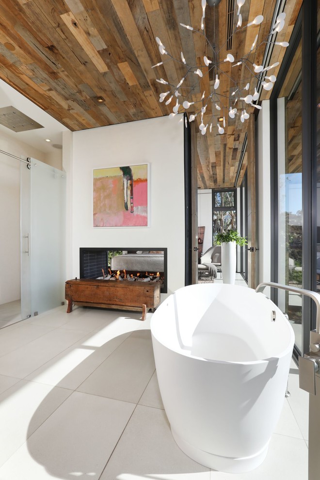 This is an example of a large contemporary master bathroom in Orange County with light wood cabinets, a freestanding tub, an open shower, a one-piece toilet, white walls, porcelain floors, solid surface benchtops, beige floor and white benchtops.
