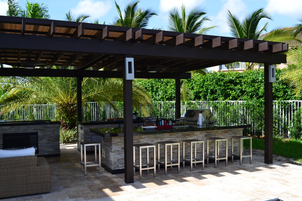 Design ideas for an expansive mediterranean backyard patio in Miami with an outdoor kitchen, natural stone pavers and a pergola.