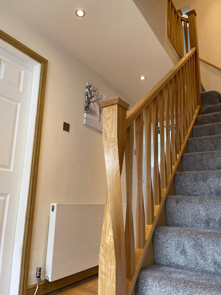 Idée de décoration pour un escalier design en L de taille moyenne avec des marches en moquette, des contremarches en moquette et un garde-corps en bois.