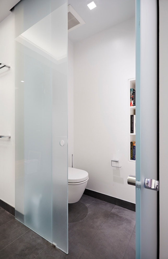 This is an example of a small modern 3/4 bathroom in New York with a wall-mount toilet, white walls, ceramic floors, raised-panel cabinets, an open shower and a drop-in sink.