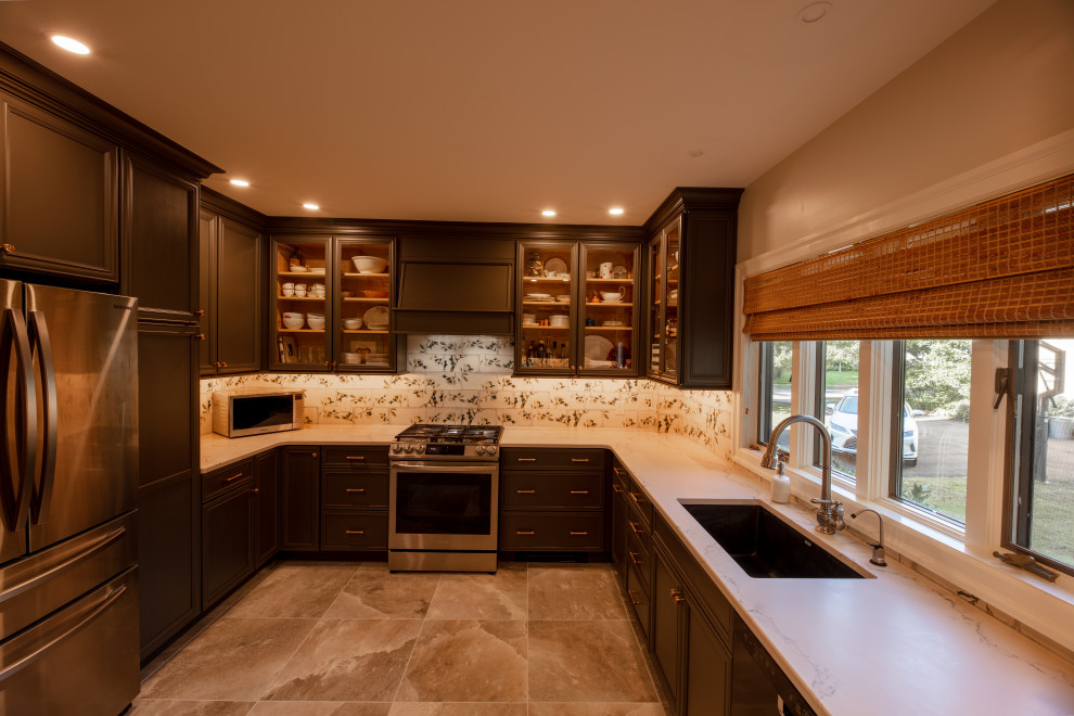 This is an example of a large classic u-shaped kitchen pantry in Philadelphia with a submerged sink, recessed-panel cabinets, brown cabinets, engineered stone countertops, white splashback, metro tiled splashback, stainless steel appliances, porcelain flooring, no island, multi-coloured floors and white worktops.