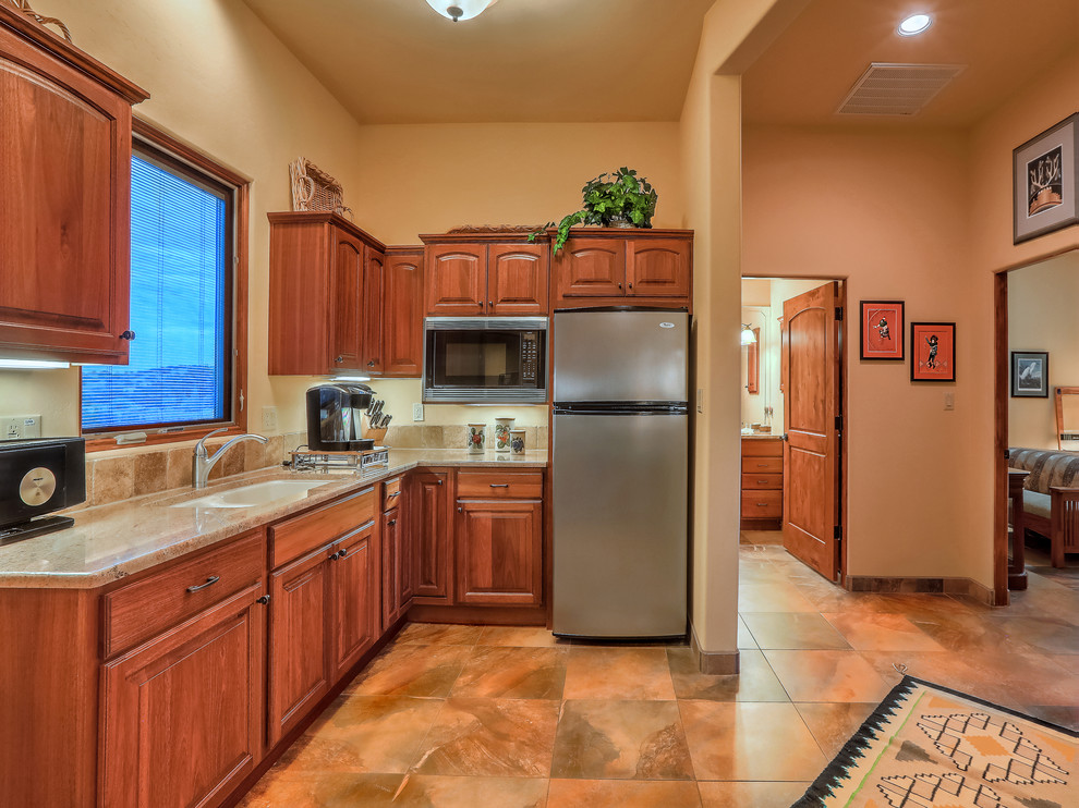 This is an example of a small l-shaped kitchen pantry in Albuquerque with an undermount sink, recessed-panel cabinets, medium wood cabinets, granite benchtops, beige splashback, ceramic splashback, stainless steel appliances, travertine floors and beige floor.