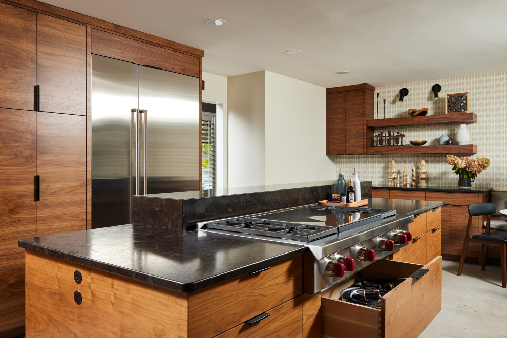 Example of a large transitional u-shaped porcelain tile and gray floor enclosed kitchen design in Minneapolis with a farmhouse sink, flat-panel cabinets, medium tone wood cabinets, granite countertops, gray backsplash, ceramic backsplash, stainless steel appliances, an island and black countertops