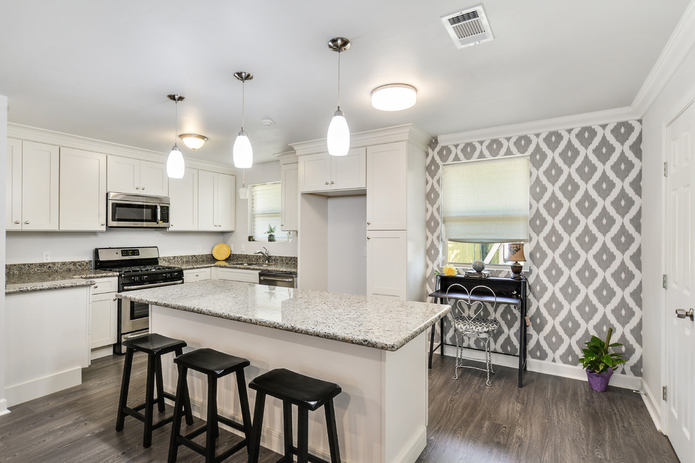 Photo of a small contemporary l-shaped eat-in kitchen in New Orleans with an undermount sink, shaker cabinets, white cabinets, glass benchtops, stainless steel appliances, laminate floors and with island.