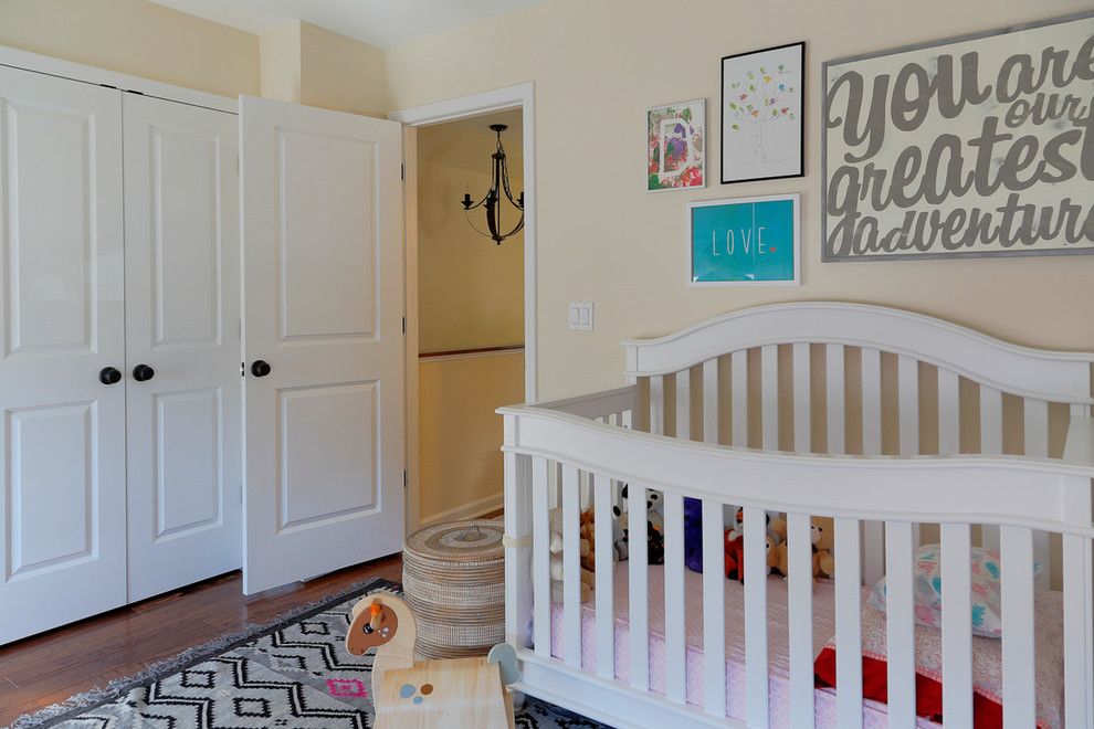 Photo of a mid-sized traditional nursery for girls in New York with beige walls, medium hardwood floors and brown floor.