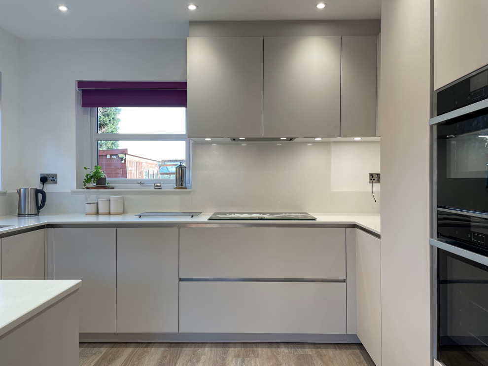 Inspiration for a medium sized contemporary u-shaped enclosed kitchen in Other with an integrated sink, flat-panel cabinets, quartz worktops, white splashback, medium hardwood flooring, no island and white worktops.