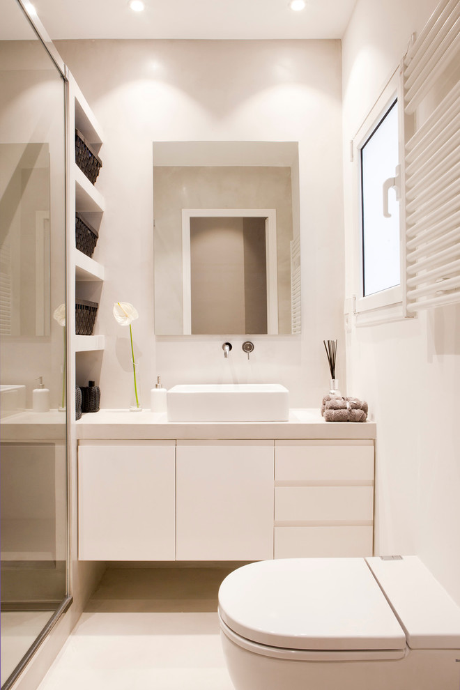 Design ideas for a mid-sized mediterranean powder room in Barcelona with flat-panel cabinets, white cabinets, a one-piece toilet, white walls and a vessel sink.