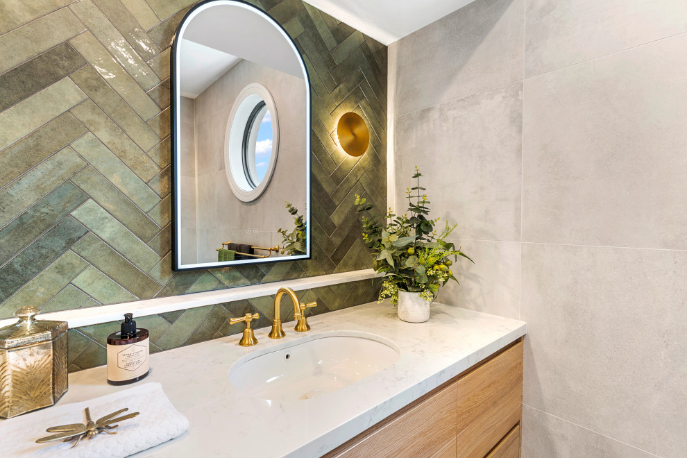 Aménagement d'un WC et toilettes classique en bois clair de taille moyenne avec un carrelage vert, des carreaux de céramique, un mur beige, un lavabo encastré, un plan de toilette en quartz modifié et un plan de toilette blanc.