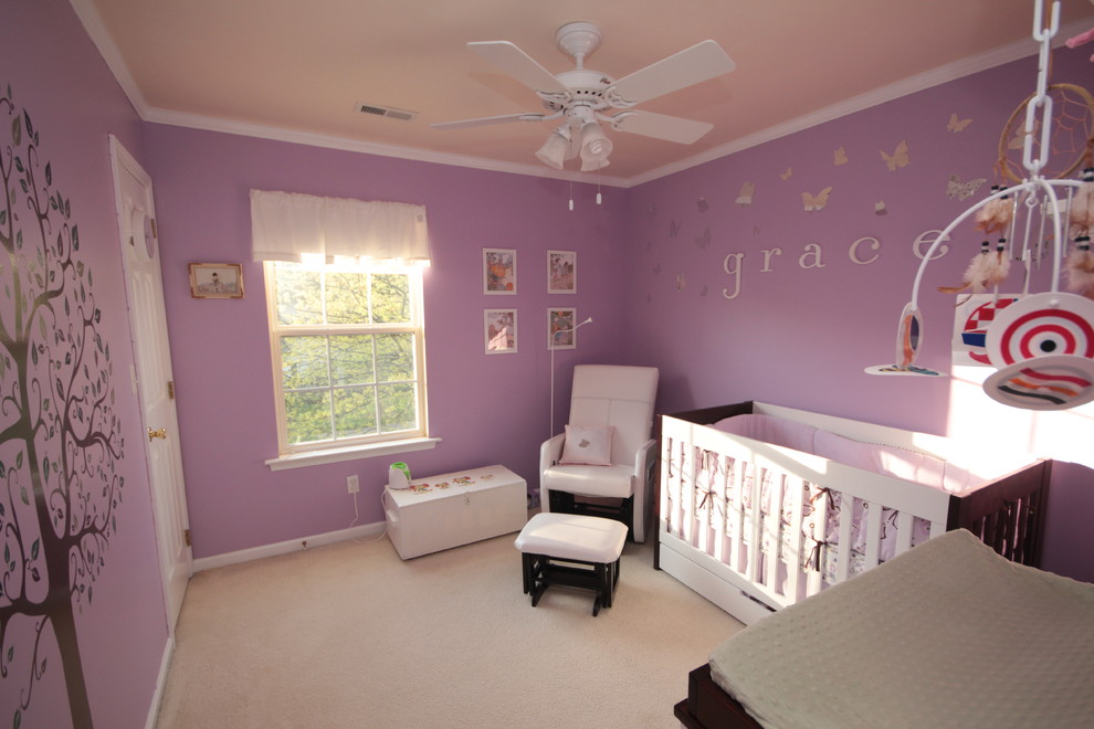 This is an example of a small contemporary nursery for girls in Charlotte with purple walls and carpet.